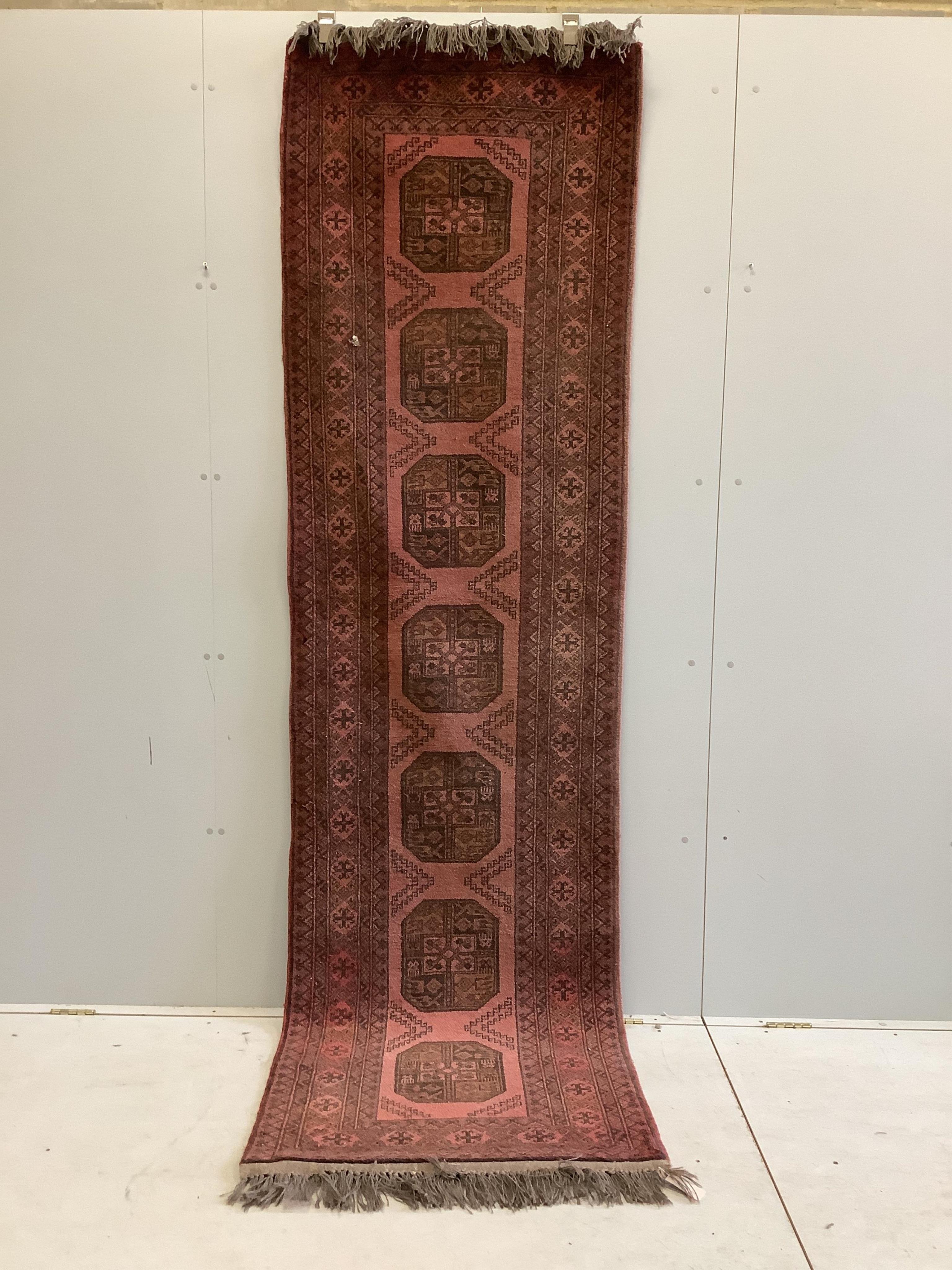 An Afghan red ground runner, 294 x 80cm. Condition - fair